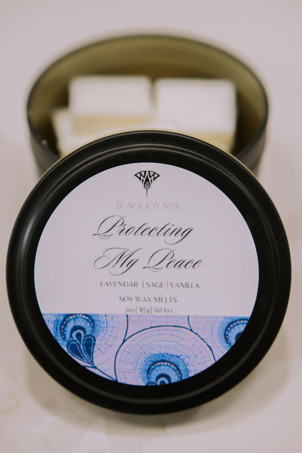 black metal tin with 16 Lavender Sage and Vanilla scented wax melts inside. the tin lid has a purple label on it with the words "Protecting My Peace" on it.