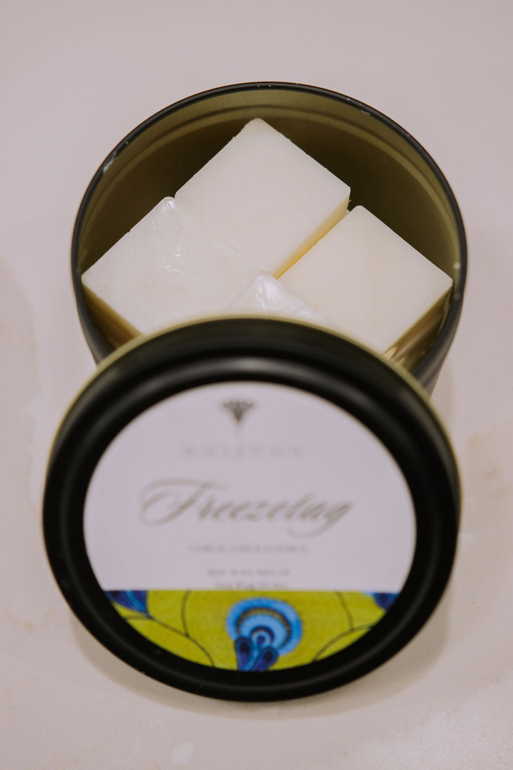 black metal tin with 16 fruit loop scented soy wax melts inside. The tin has a bright green label with the word "Freezetag" written on it.