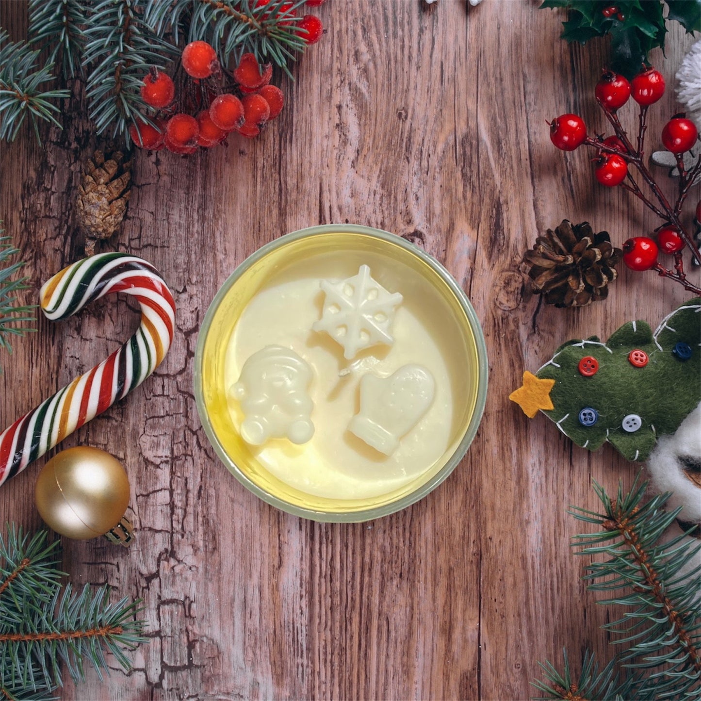 Decorative scented soy candle with Christmas-themed decorations on a wooden surface