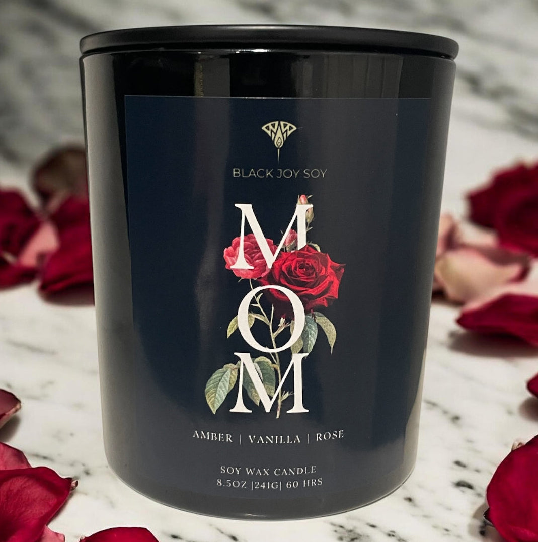 Black candle jar with 'Mom' text and rose design on a marble surface with red rose petals. Mothers Day candle, Mothers day gift. Rose, vanilla and amber scented soy candle.