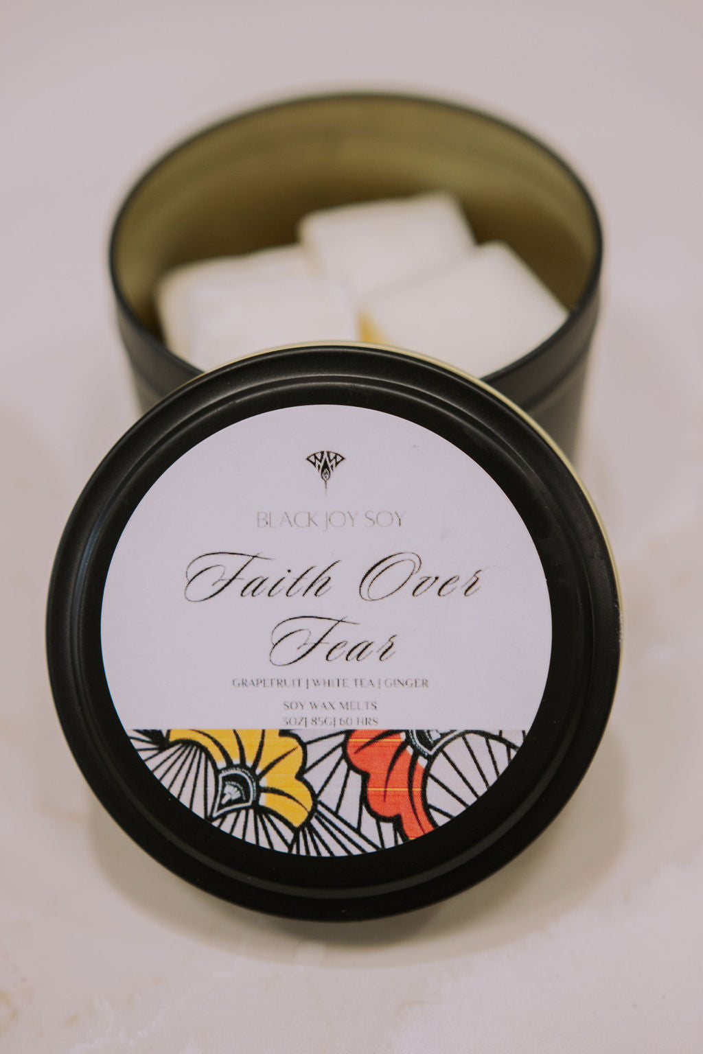 black metal tin with 16 Grapefruit, white tea & ginger scented soy wax melts inside. The tin has a label with the words "Faith Over Fear" written on it.