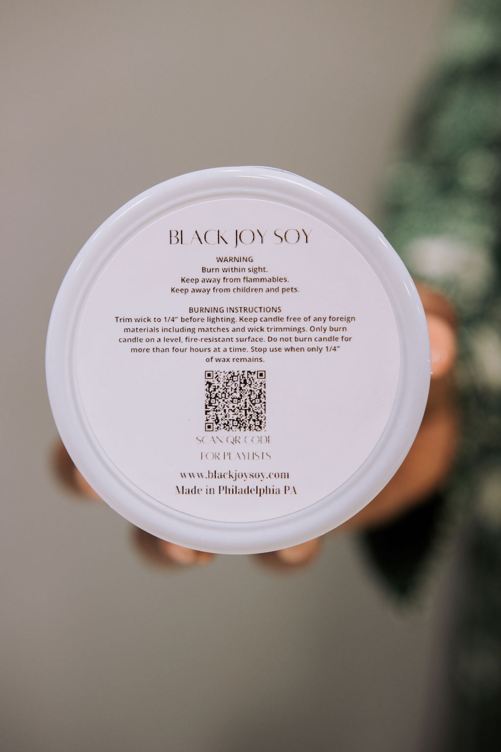 Warning label with QR code that links to  list of curated playlist that accompany each Black Joy Soy scent